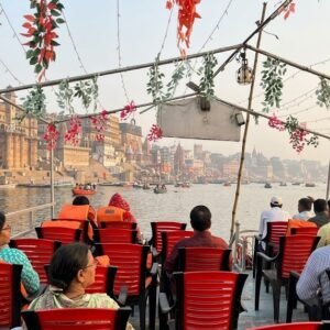 Passengers on a decorated boat ride past Varanasi's ghats.